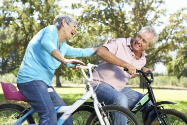 Senior couple playing on children's bikes clipart