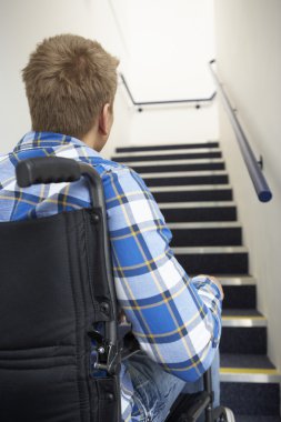 Man in wheelchair at foot of stairs clipart