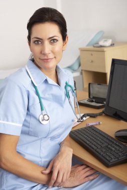 British nurse sitting at desk at work clipart