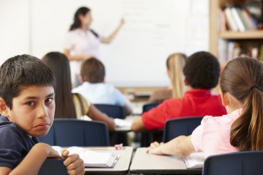 Unhappy schoolboy in class clipart