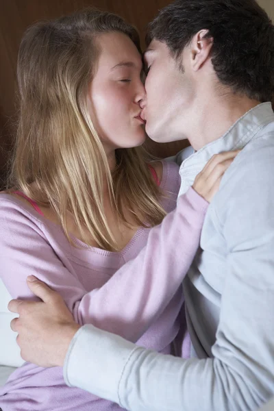 Casal adolescente romântico beijando no sofá em casa juntos — Fotografia de Stock