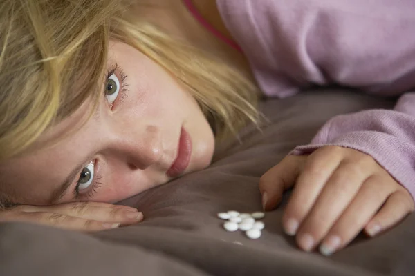 Depressief tiener meisje zit in de slaapkamer met pillen — Stockfoto