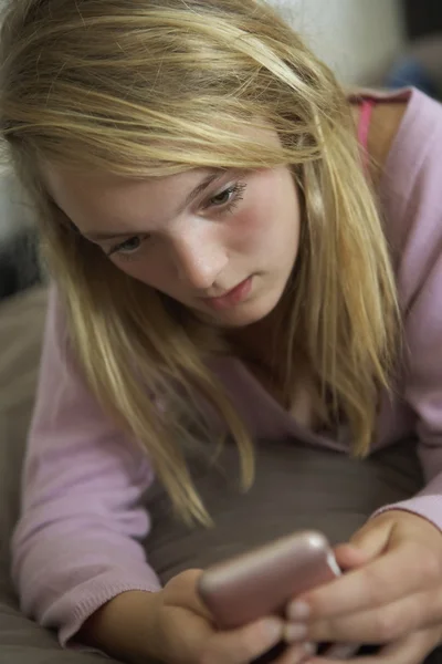 Olycklig tonårstjej ligga i sovrummet med mobiltelefon — Stockfoto