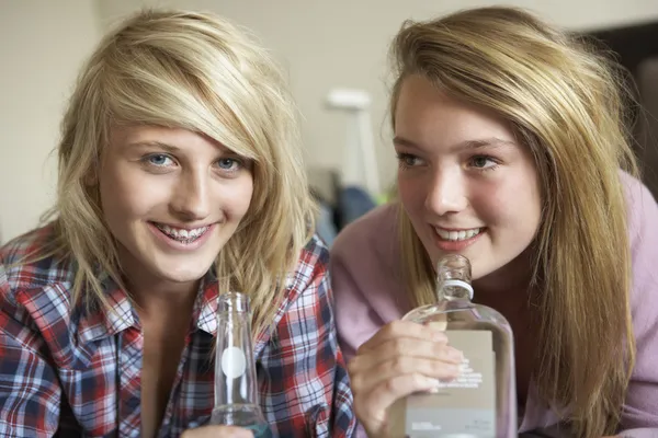 Twee tienermeisjes zittend op de Bank thuis drinken van alcohol — Stockfoto