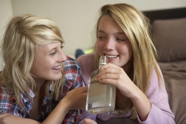 Dvě mladé dívky sedí na gauči doma pije alkohol — Stock fotografie