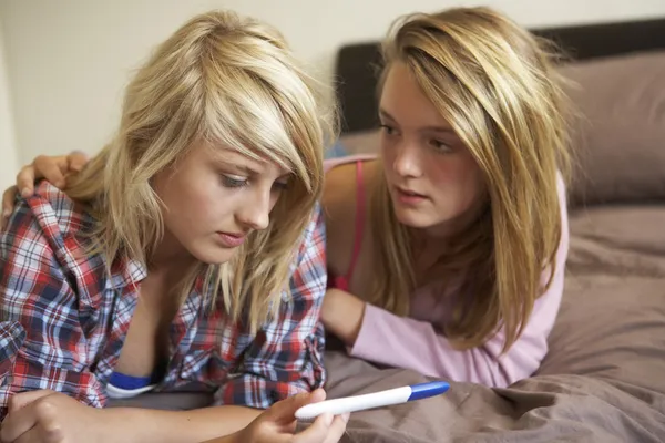 Due ragazze adolescenti sdraiate sul letto guardando il kit di test di gravidanza — Foto Stock