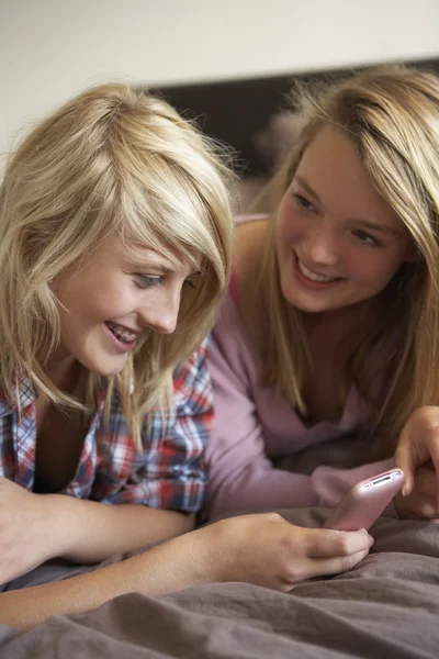 Zwei Teenager-Mädchen liegen mit Handy im Bett — Stockfoto