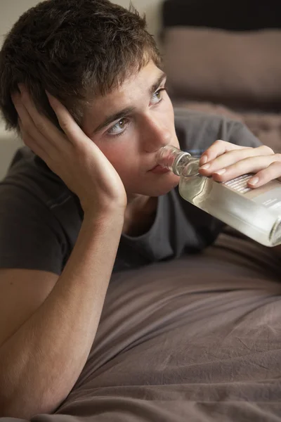 Dospívající chlapec ležící v ložnici pití — Stock fotografie
