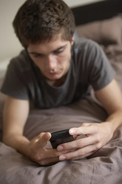 Infeliz adolescente acostado en el dormitorio con teléfono móvil — Foto de Stock