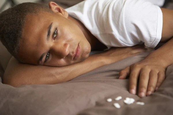 Deprimido adolescente deitado no quarto com pílulas — Fotografia de Stock
