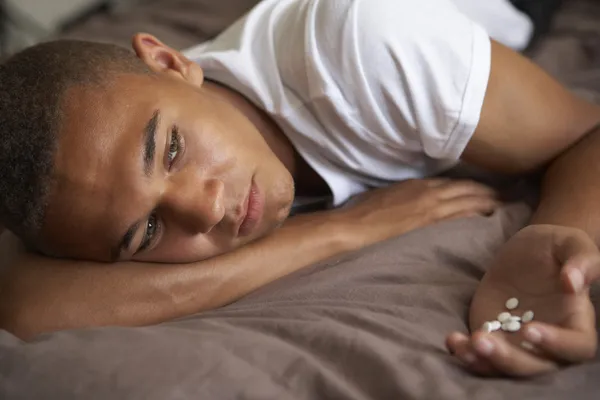Depressief tiener liggen in slaapkamer met pillen — Stockfoto