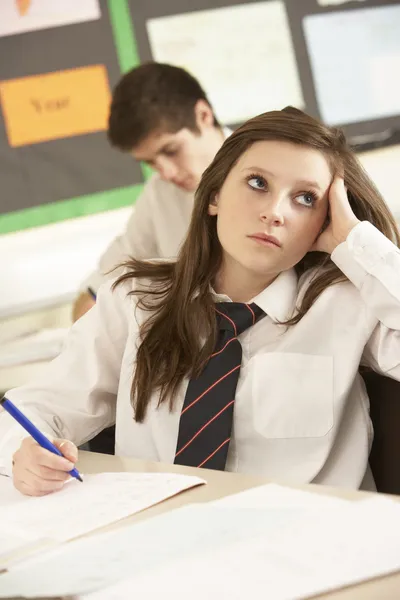 Uttråkad kvinnliga tonåriga student som studerar i klassrummet — Stockfoto