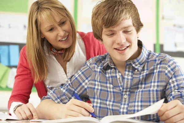 Manliga teenage student som studerar i klassrummet med lärare — Stockfoto