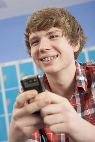 Hombre adolescente estudiante usando teléfono móvil por casilleros en la escuela — Foto de Stock