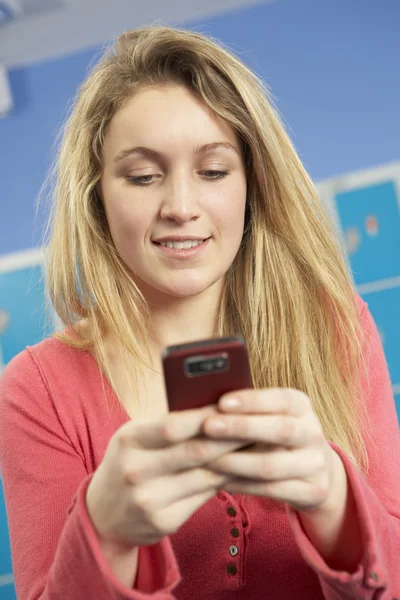Estudiante adolescente usando teléfono móvil por casilleros en la escuela —  Fotos de Stock