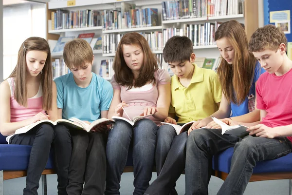 Estudiantes adolescentes en la biblioteca leyendo libros — Foto de Stock