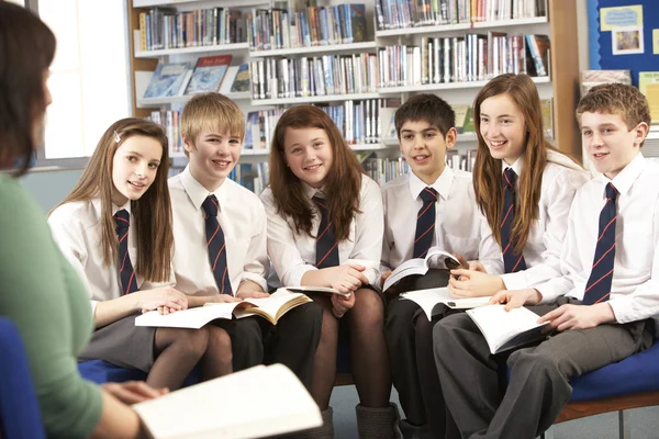 Estudantes adolescentes em livros de leitura de biblioteca com professor — Fotografia de Stock
