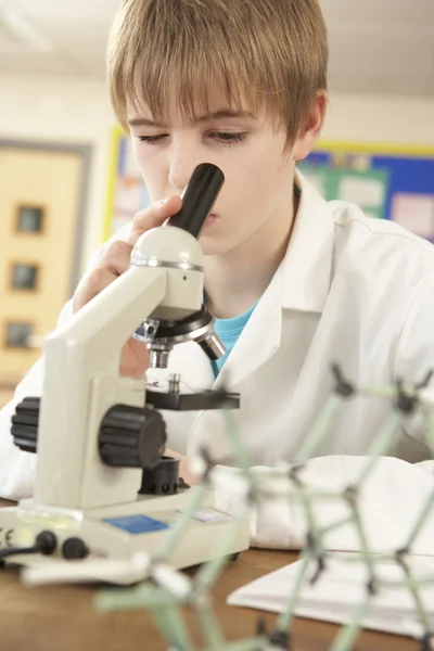 Учащийся-подросток в классе естественных наук смотрит в микроскоп — стоковое фото