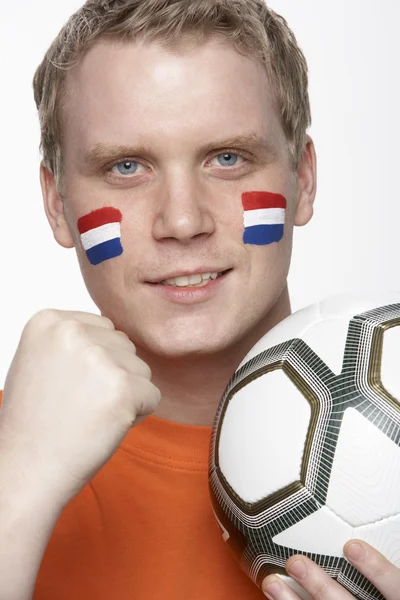 Ventilador de fútbol masculino joven con bandera holandesa pintada en la cara — Foto de Stock