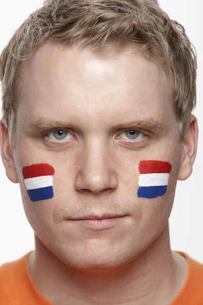 Молодой фанат спорта с голландским флагом, раскрашенным на лице — стоковое фото