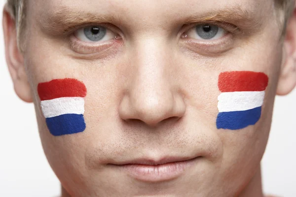 Ventilador deportivo masculino joven con bandera holandesa pintada en la cara —  Fotos de Stock