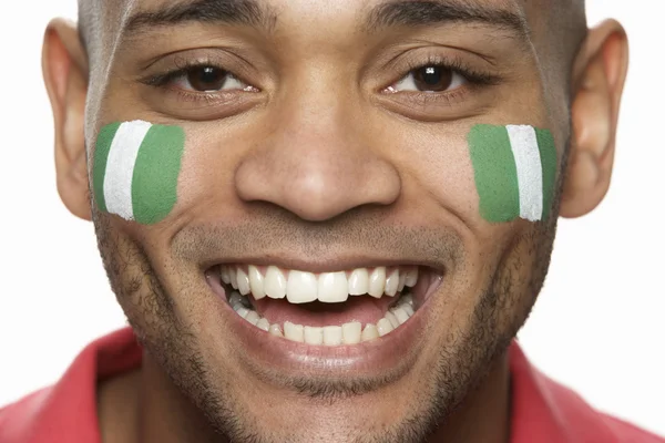 Fiatal férfi sport rajongó arcán festett nigériai zászló — Stock Fotó