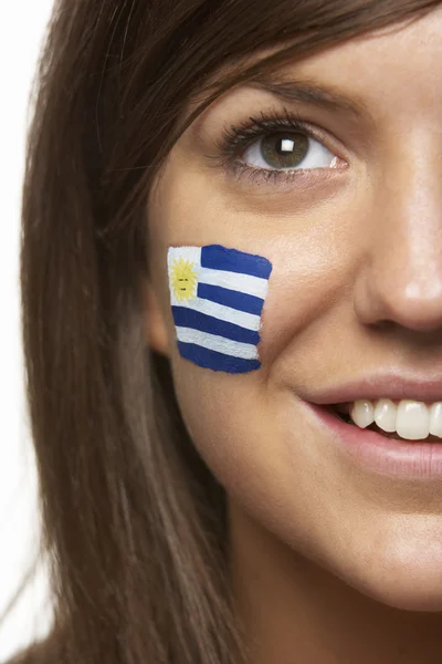 Ventilador deportivo femenino joven con bandera uruguaya pintada en la cara — Foto de Stock