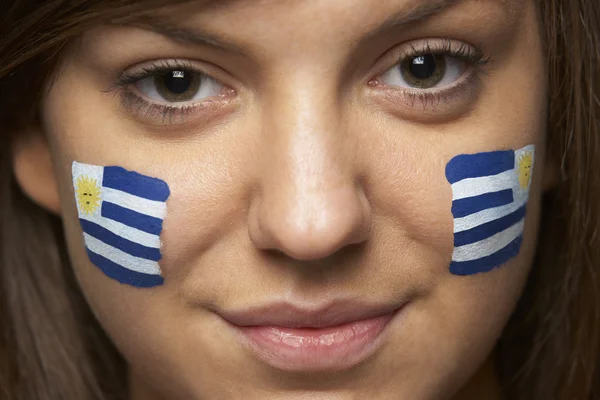 Ventilador deportivo femenino joven con bandera uruguaya pintada en la cara — Foto de Stock