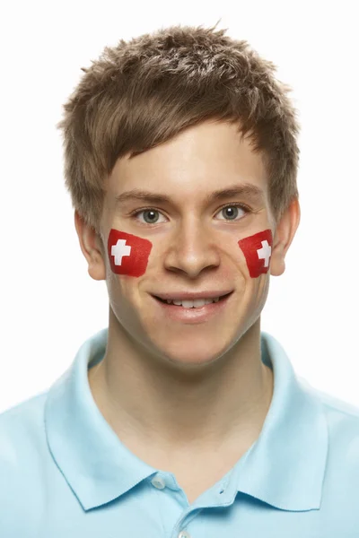 Junger männlicher Sportfan mit Schweizer Fahne im Gesicht — Stockfoto