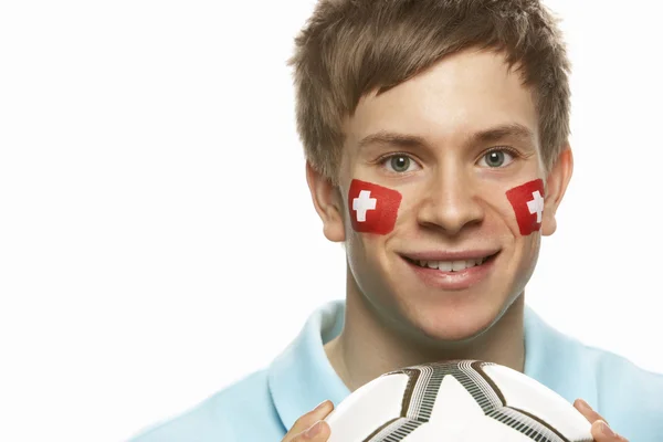 Fiatal férfi focirajongó festett arca svájci zászló — Stock Fotó
