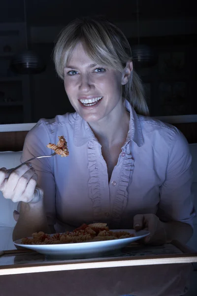Женщина наслаждается едой во время просмотра телевизора — стоковое фото