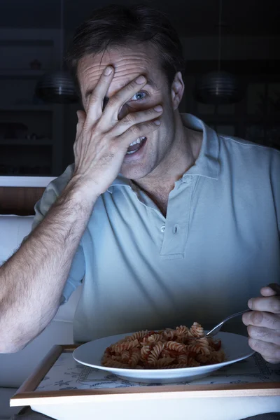 Homme effrayé appréciant les repas tout en regardant la télévision — Photo