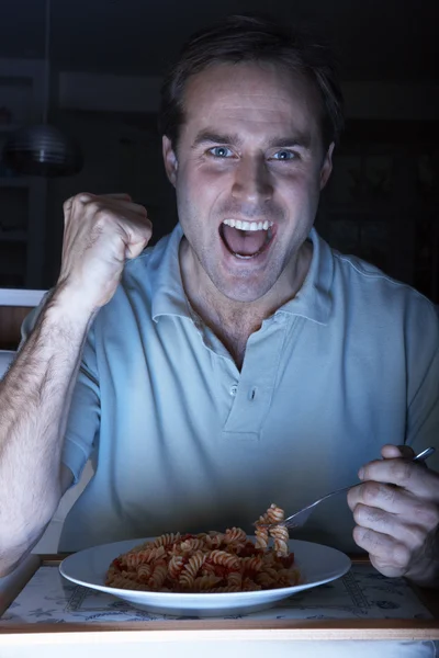 Muž užívat jídlo a fandění během sledování tv — Stock fotografie
