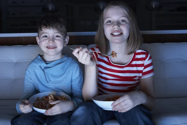 Niños disfrutando de la comida mientras ven la televisión —  Fotos de Stock