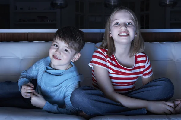 Дети смотрят телевизор вместе, сидя на диване — стоковое фото