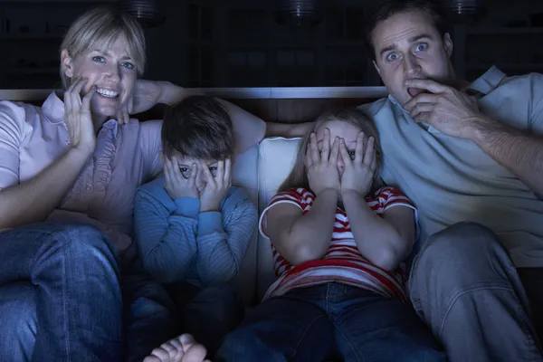 家族一緒にソファに座ってテレビで怖いプログラムを見て — ストック写真