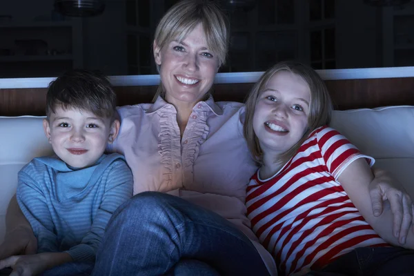 Matka i dzieci oglądania programu tv siedząc na kanapie tog — Zdjęcie stockowe