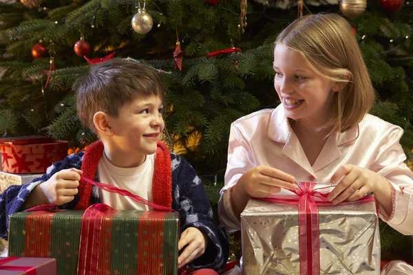 Děti otevírání vánoční dárek před strom — Stock fotografie