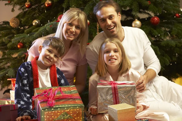 Familia abriendo regalo de Navidad delante del árbol —  Fotos de Stock