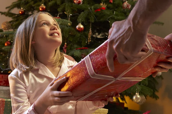 Menina jovem recebendo presente de Natal na frente da árvore — Fotografia de Stock