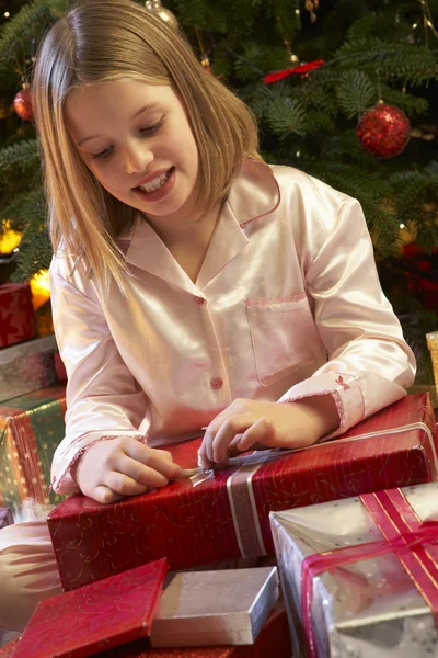 Jong meisje openen kerstcadeau voor boom — Stockfoto