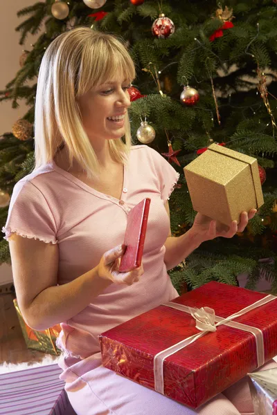 Mujer abriendo regalo de Navidad delante del árbol —  Fotos de Stock