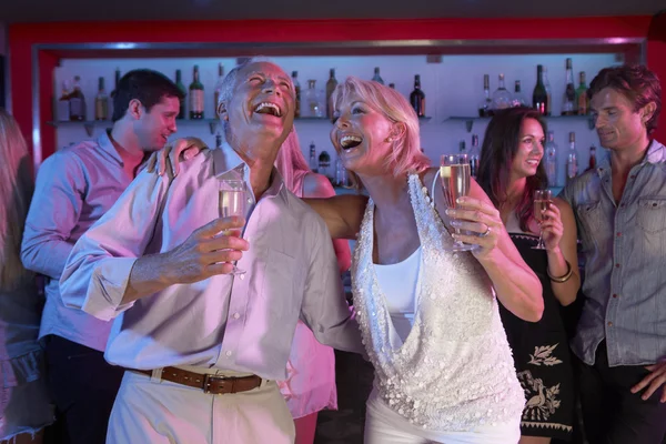 Pareja mayor divirtiéndose en el bar ocupado — Foto de Stock