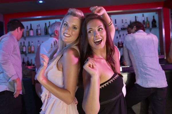 Deux jeunes femmes s'amusent dans un bar occupé — Photo