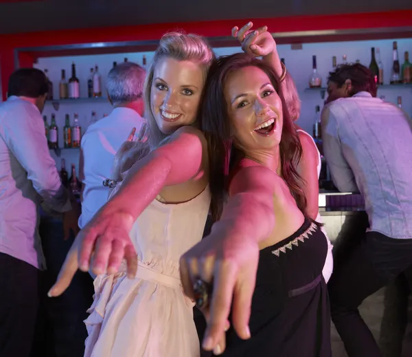 Dos mujeres jóvenes divirtiéndose en el bar ocupado — Foto de Stock