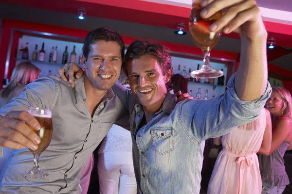 Deux jeunes hommes s'amusent dans un bar occupé — Photo