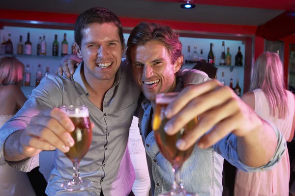 Två unga män ha kul i upptagen bar — Stockfoto