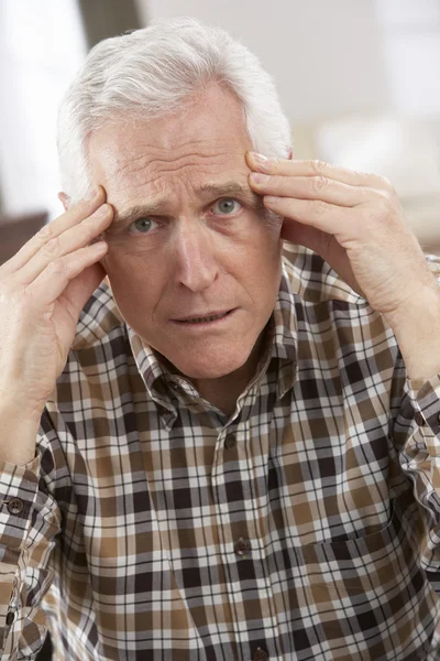 Hombre mayor mirando estresado en silla en casa — Foto de Stock