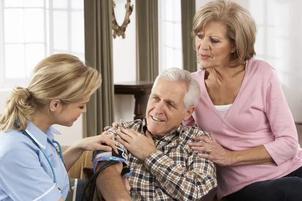 Gezondheid bezoeker nemen senior man bloeddruk — Stockfoto
