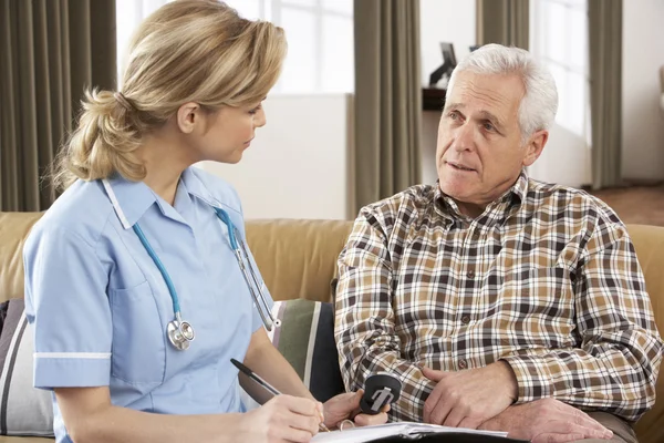 Hombre mayor hablando con el visitador de salud en casa —  Fotos de Stock